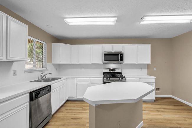Rows of cabinets for storage and countertops space for preparing meals in the lovely kitchen. | Image 12