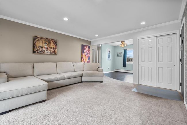 Carpeted living area with a baseboard radiator, recessed lighting, ornamental molding, and ceiling fan | Image 9