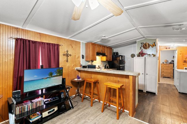 Kitchen featuring wood finished floors, under cabinet range hood, wooden walls, vaulted ceiling, and freestanding refrigerator | Image 8