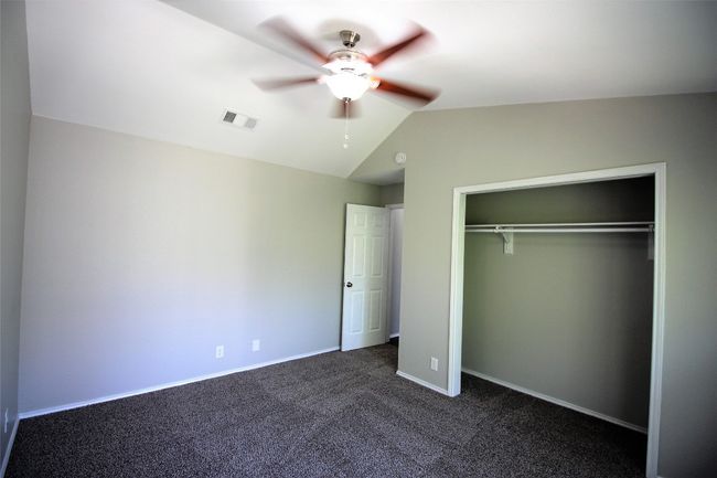 Unfurnished bedroom with lofted ceiling, a closet, dark colored carpet, and ceiling fan | Image 12