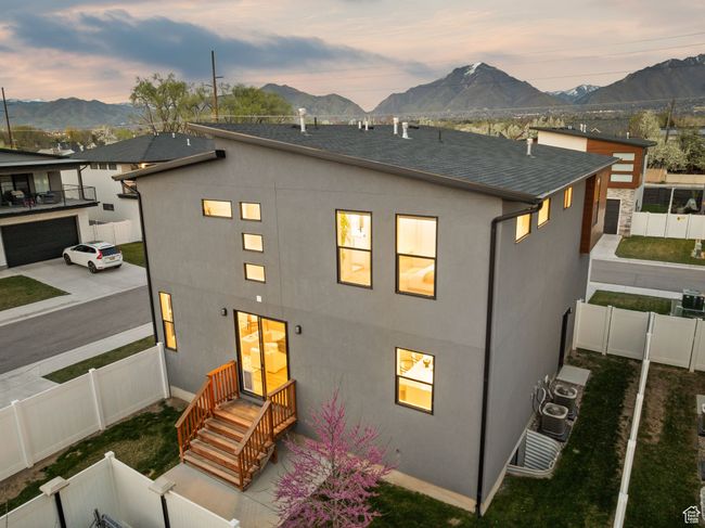 Back of house at dusk with a shingled roof, a fenced backyard, stucco siding, and a mountain view | Image 39