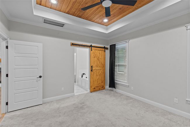 Unfurnished bedroom featuring ornamental molding, a barn door, wooden ceiling, carpet flooring, and recessed lighting | Image 12