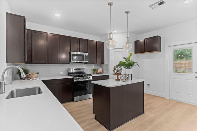 A second angle reveals the kitchen’s seamless connection to the dining and living areas, with contemporary finishes and a central island that anchors the heart of the home. **Image Representative of Plan Only and May Vary as Built**. | Image 12
