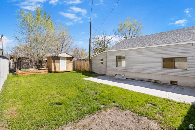 View of yard featuring a patio area, a fenced backyard, an outdoor structure, and a storage unit | Image 51