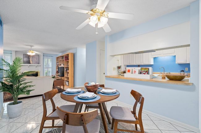 Dining room featuring a textured ceiling, ceiling fan, a fireplace, and baseboards | Image 12