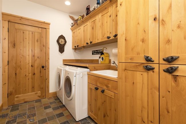 Entry level laundry room with front loading washer and dryer, cabinets, sink, with entry door to mechanical room. | Image 61
