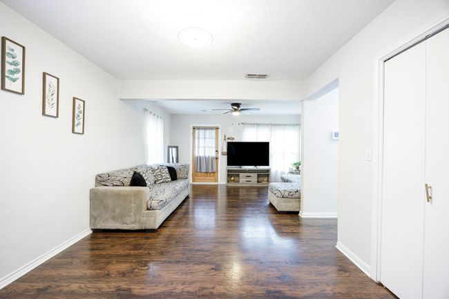 Unfurnished living room featuring visible vents, baseboards, a ceiling fan, and wood finished floors | Image 8