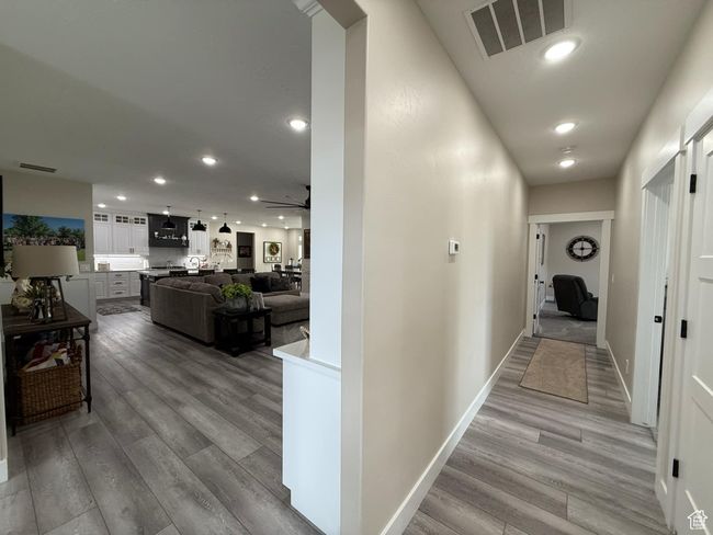 Hallway with baseboards, recessed lighting, visible vents, and light wood-style floors | Image 16