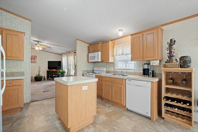 Kitchen with white appliances, vaulted ceiling, a sink, open floor plan, and a textured ceiling | Image 13