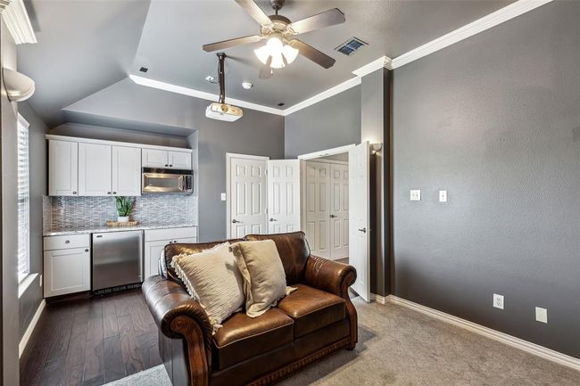 Living room with ceiling fan, dark carpet, crown molding, and vaulted ceiling | Image 22