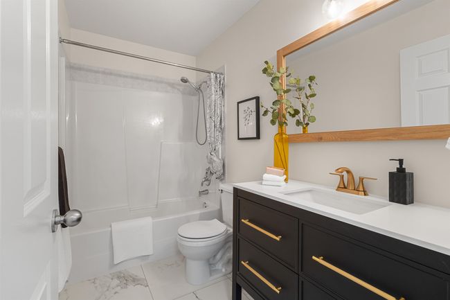 Bathroom with vanity, marble look tiles, shower / bath combination with curtain, and toilet | Image 22