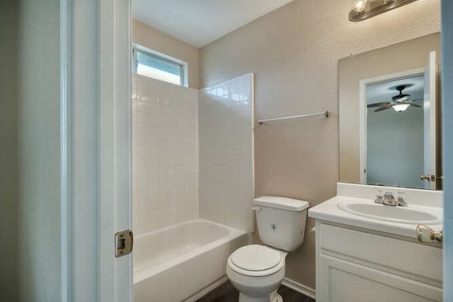 Bathroom with toilet, vanity, washtub / shower combination, and ceiling fan | Image 8