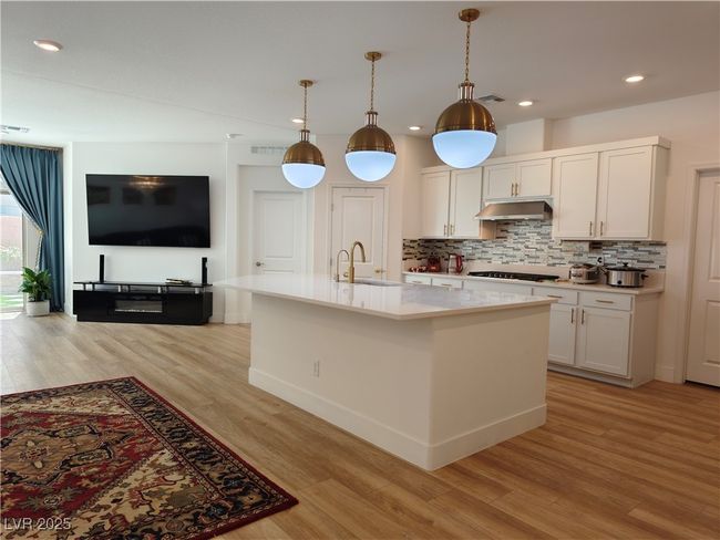 Kitchen featuring light wood-type flooring, tasteful backsplash, light countertops, and a sink | Image 13