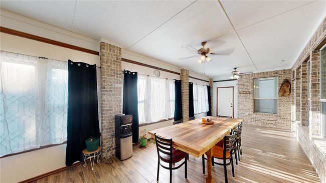 Dining area featuring wood finished floors, a ceiling fan, and brick wall | Image 24