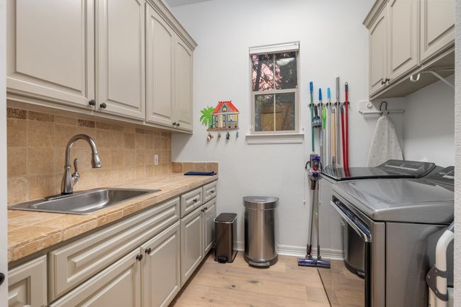 Laundry area featuring cabinet space, independent washer and dryer, and light wood-type flooring | Image 29