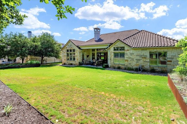 Rear view of property with stone siding, a tiled roof, a chimney, and a patio area | Image 32