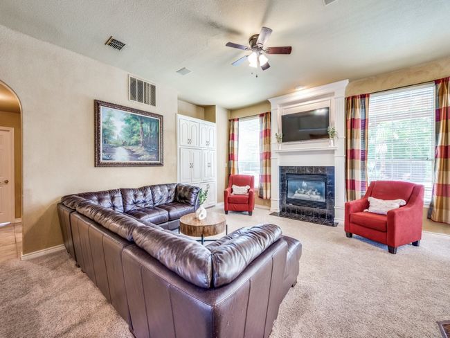 Living room with light carpet, a ceiling fan, a tile fireplace, and arched walkways | Image 9