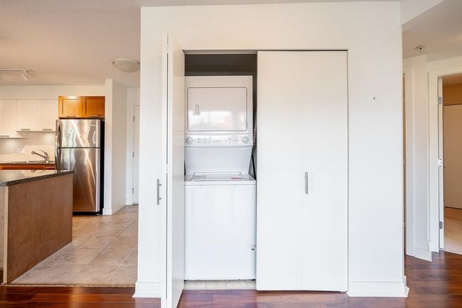 Washroom with stacked washer and dryer, light wood finished floors, a sink, and laundry area | Image 17