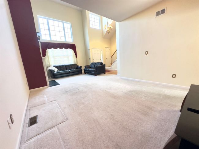 Carpeted living area featuring a gas Fireplace , a towering ceiling, an inviting chandelier, and stairs | Image 9