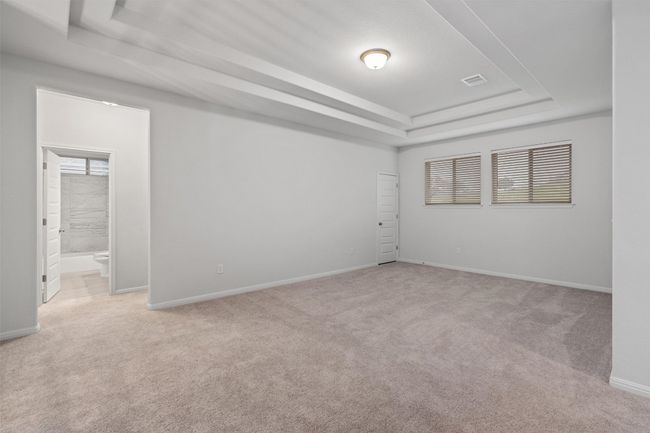 Spare room featuring baseboards, a tray ceiling, visible vents, and light colored carpet | Image 22