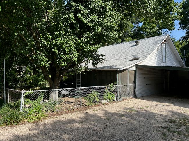 View of front facade featuring an attached carport, a shingled roof, driveway, and a sunroom | Image 4