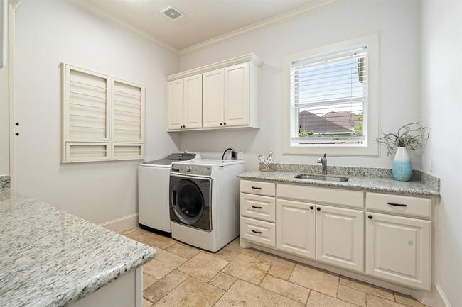 This spacious Laundry Room will make it easy to fight tough stains and sort multiple loads of laundry. The space comes equipped with an undermount, stainless steel sink, granite countertop, under and above cabinet storage, as well as a built-in, drop-down storage rack. The side-facing window adds natural light and a pretty view. | Image 24
