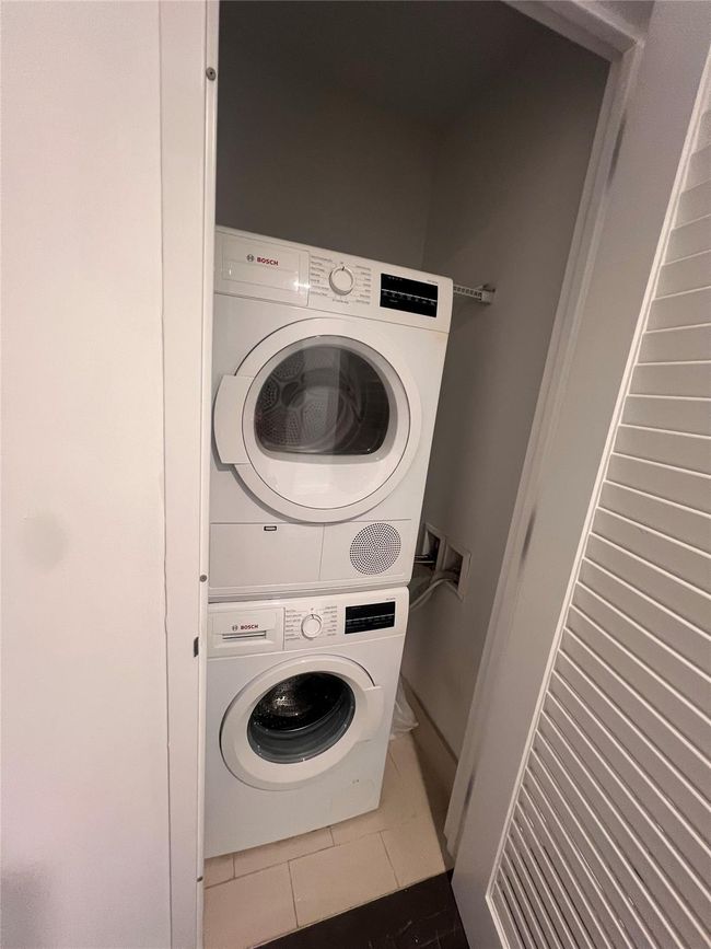 Laundry room with stacked washer / dryer and tile patterned floors | Image 8