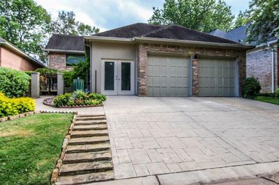 This is a single-story residence featuring a two-car garage, a spacious driveway, and a well-manicured front garden with a walkway leading to the main entrance. The home presents a blend of brick and siding exterior finishes. | Image 2