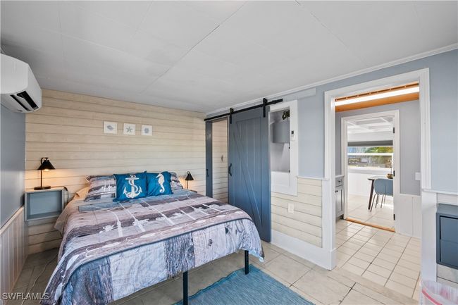 Tiled bedroom with a wall mounted air conditioner, wood walls, ornamental molding, and a barn door | Image 26