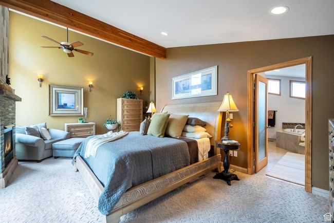 Carpeted bedroom featuring a fireplace, lofted ceiling with beams, recessed lighting, and baseboards | Image 31