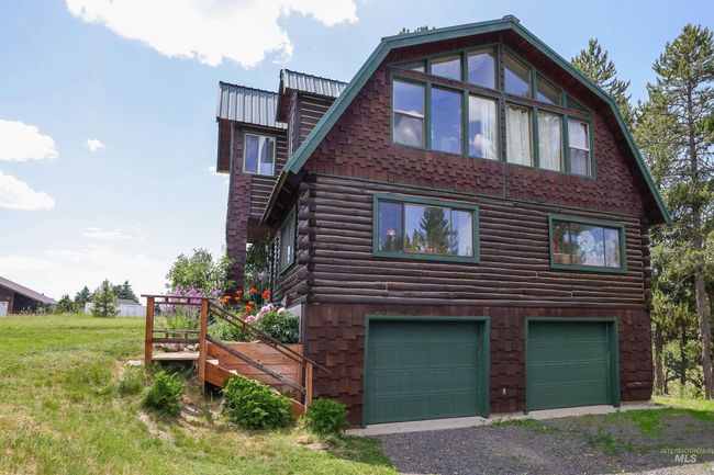 View of home's exterior with log exterior, a garage, driveway, and a gambrel roof | Image 43