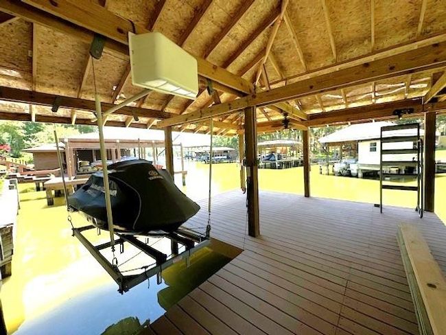 Enjoy seamless lake access with a boathouse featuring a jet ski lift, spacious deck, and convenient metal stairs. | Image 43