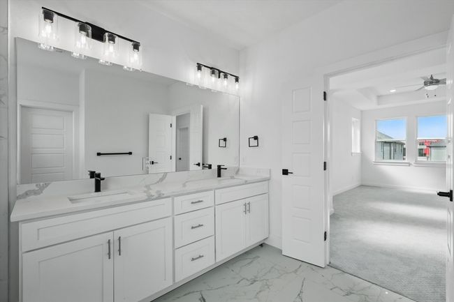 Full bathroom with double vanity, a ceiling fan, marble look tiles, and baseboards | Image 24
