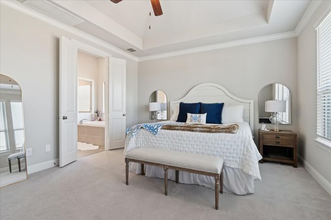 Bedroom featuring ensuite bathroom, a tray ceiling, carpet flooring, and visible vents | Image 13