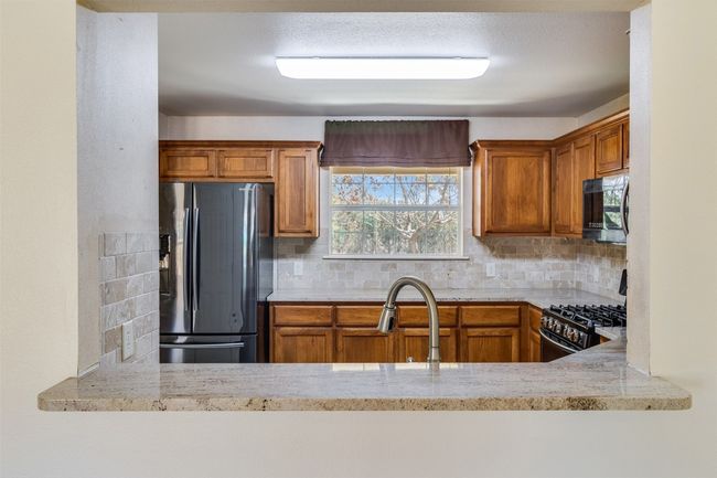 Kitchen featuring range with gas cooktop, decorative backsplash, fridge with ice dispenser, and light countertops | Image 14