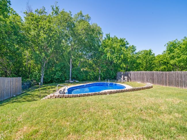 View of swimming pool featuring a yard, a fenced in pool, and a fenced backyard | Image 24