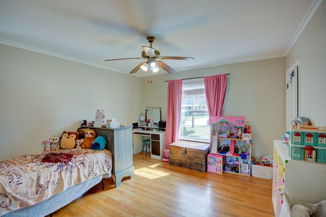 Bedroom with a ceiling fan, ornamental molding, and wood finished floors | Image 20