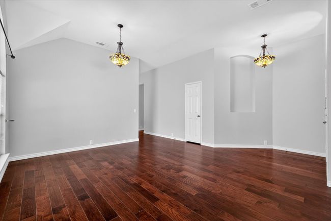 Dining room with dark wood finished floors, vaulted ceiling, and a chandelier | Image 5