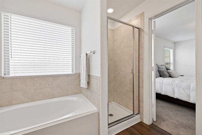 Ensuite bathroom featuring a bath, a shower stall, and wood finished floors | Image 24
