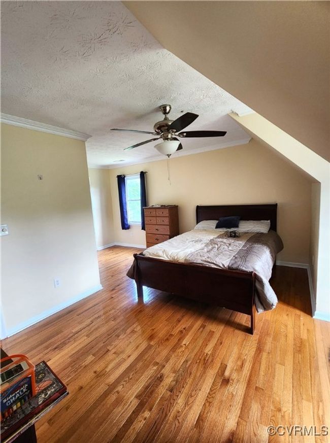 Bedroom featuring wood finished floors, ornamental molding, a textured ceiling, and a ceiling fan | Image 22