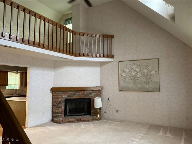Unfurnished living room featuring carpet flooring, a fireplace, and high vaulted ceiling | Image 23
