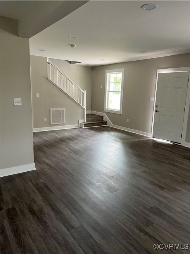 Unfurnished living room featuring baseboards, stairway, visible vents, and dark wood-style floors | Image 4