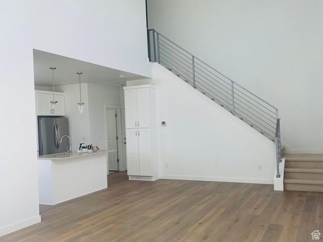 Unfurnished living room with stairway, light wood-style floors, baseboards, and a high ceiling | Image 5