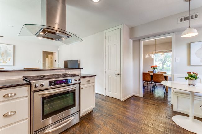 Kitchen with gas stove, island range hood, white cabinets and pendant lighting | Image 13