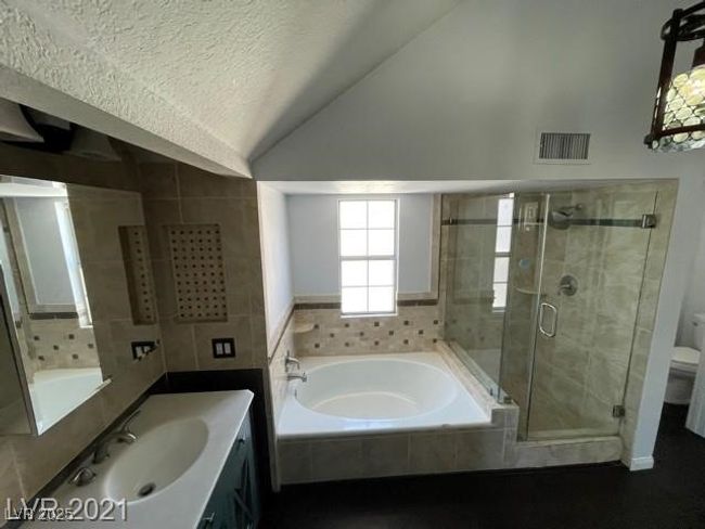 Full bathroom featuring lofted ceiling, a textured ceiling, a stall shower, a garden tub, and visible vents | Image 7