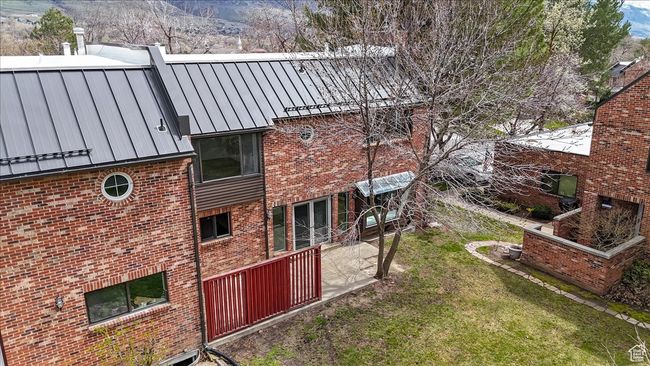 View of side of home with a standing seam roof, brick siding, metal roof, a lawn, and a mountain view | Image 43