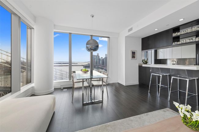 Living area with dark wood-style floors, baseboards, a city view, and visible vents | Image 6