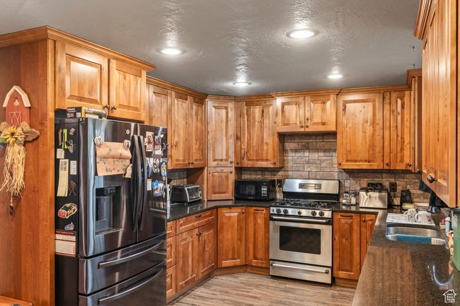 Kitchen with black appliances, a sink, brown cabinets, and backsplash | Image 9