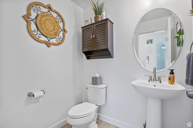 Half bath featuring wood finished floors, toilet, baseboards, and a sink | Image 29