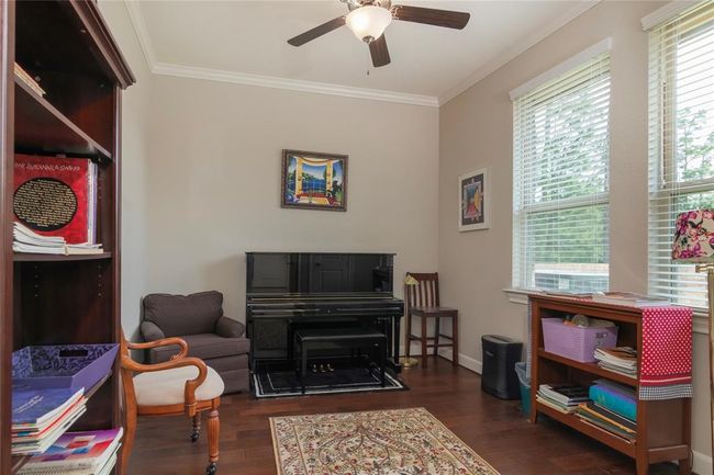 Cozy study with hardwood floors, ample natural light from large windows, and a ceiling fan. Features include French doors, crown molding, and very useful shelving added to the closet. This room could also be the fifth bedroom, downstairs playroom or even a nursery. | Image 24